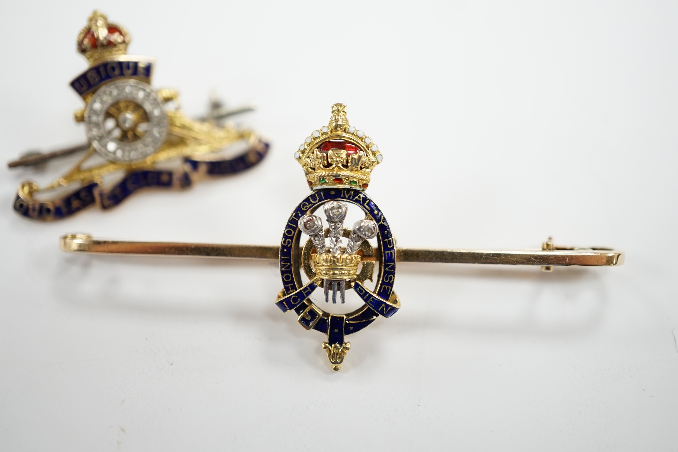 An Edwardian 15ct, enamel and rose cut diamond set Prince of Wales Order of The Garter insignia sweethearts bar brooch, 59mm and a similar yellow metal enamel and diamond chip set Royal Artillery sweethearts brooch, gros